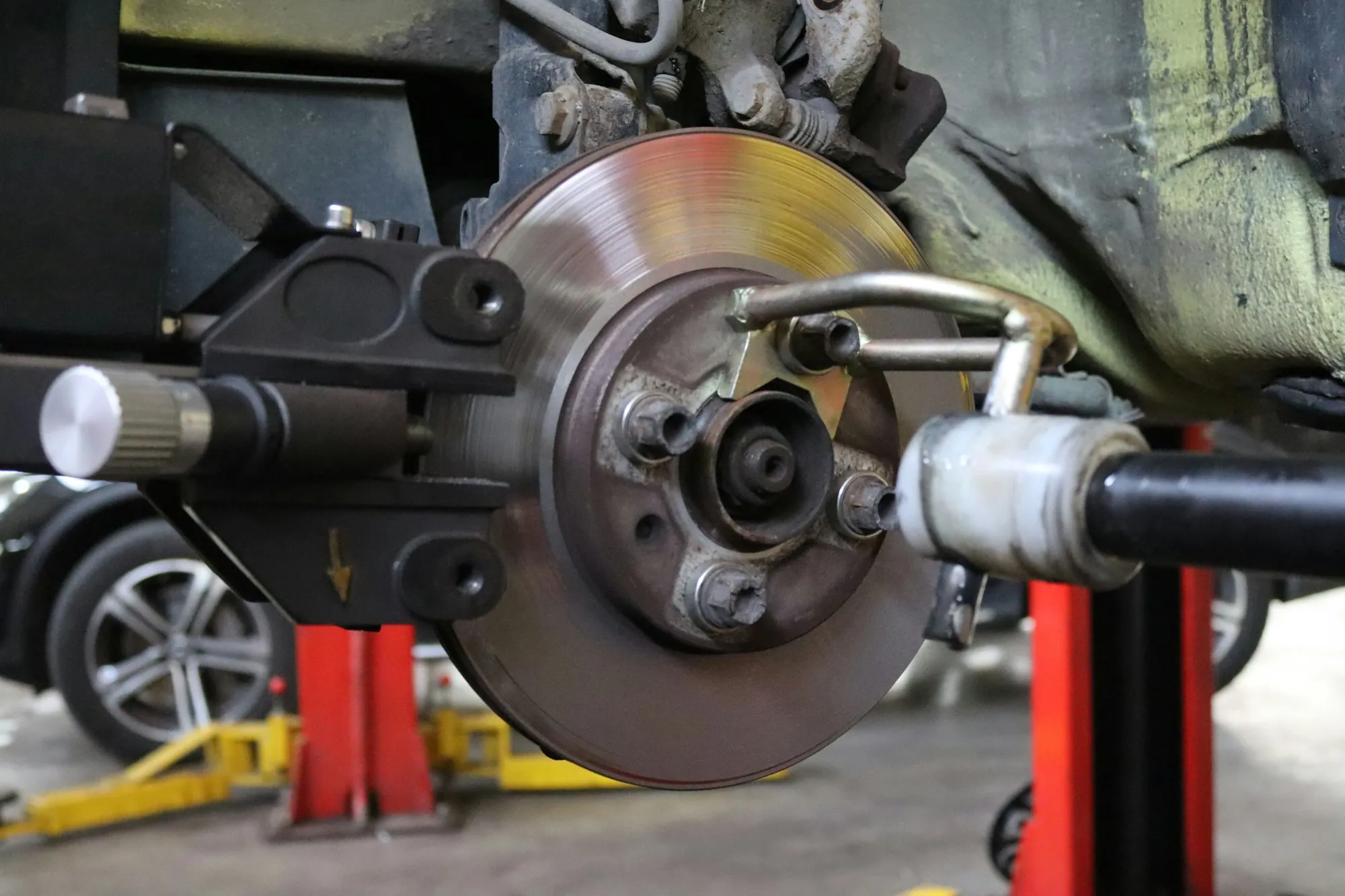 Brake disc and caliper on a raised car in a shop