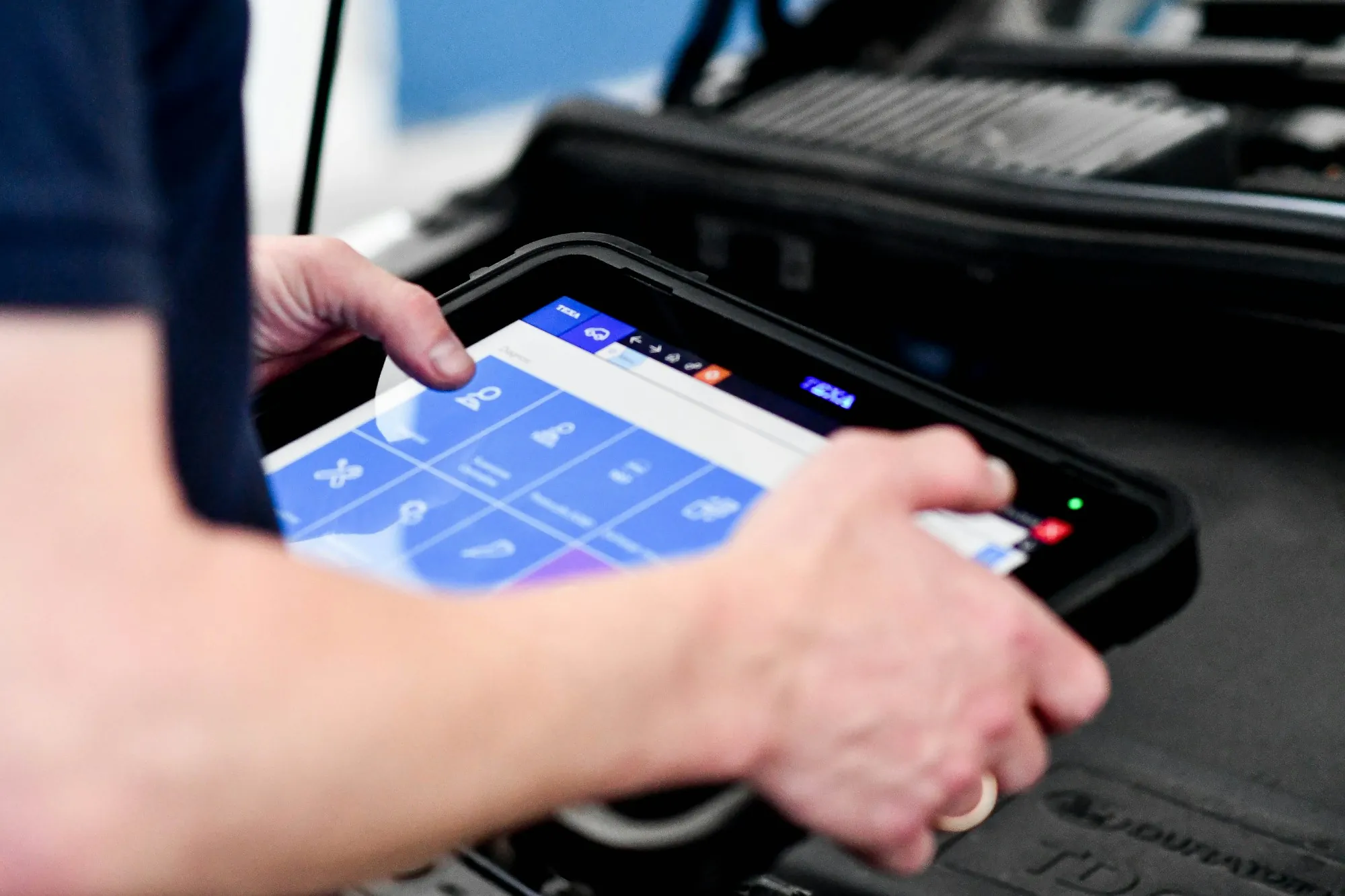 Technician holding a diagnostic tablet connected to a vehicle