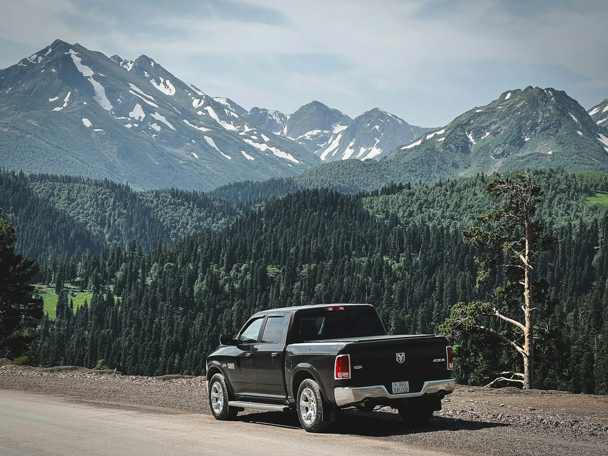 Pickup truck parked below a rocky mountain peak with pine trees